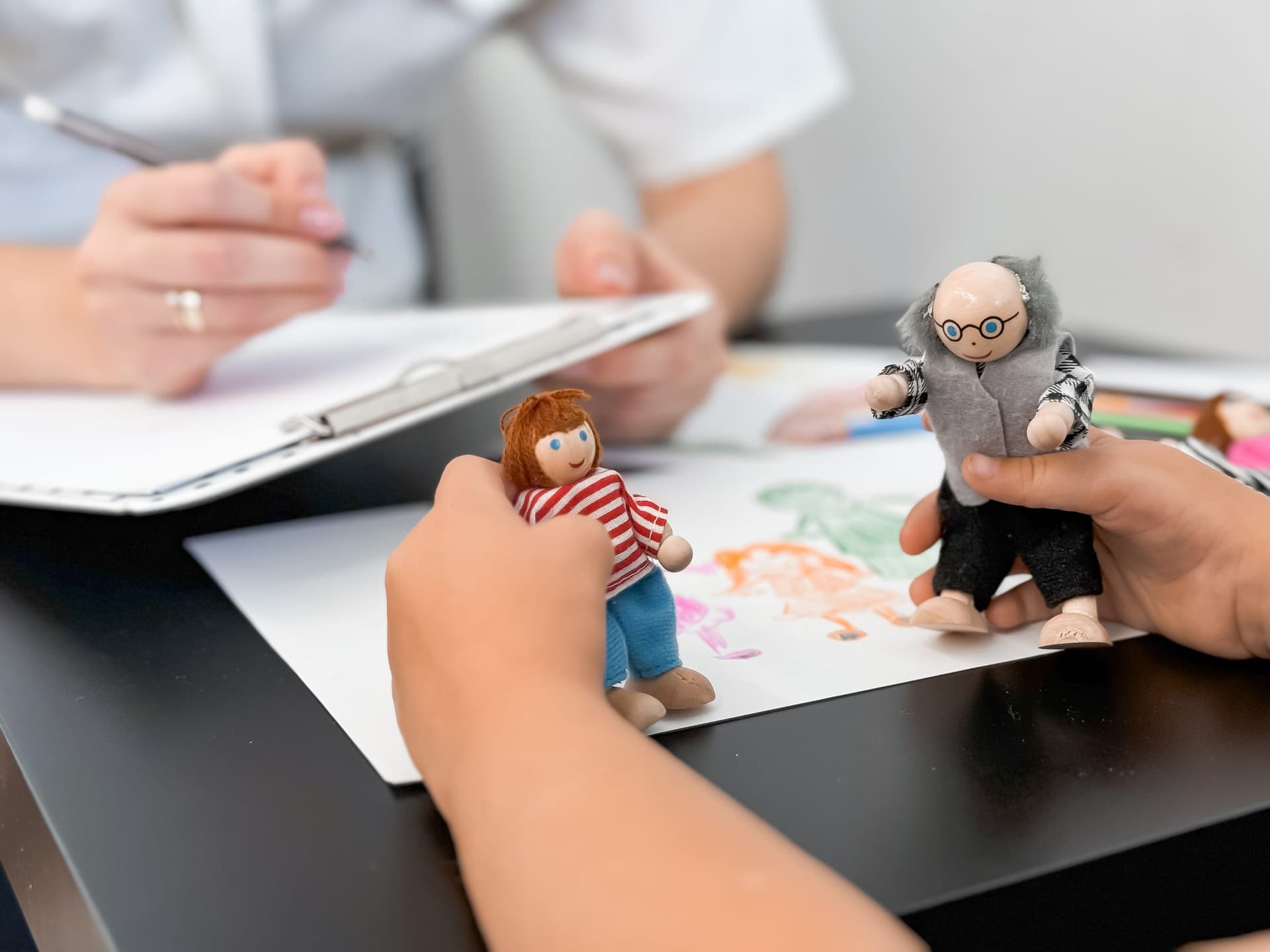 Child engaged in a play-based ABA assessment using figurines while a clinician takes notes